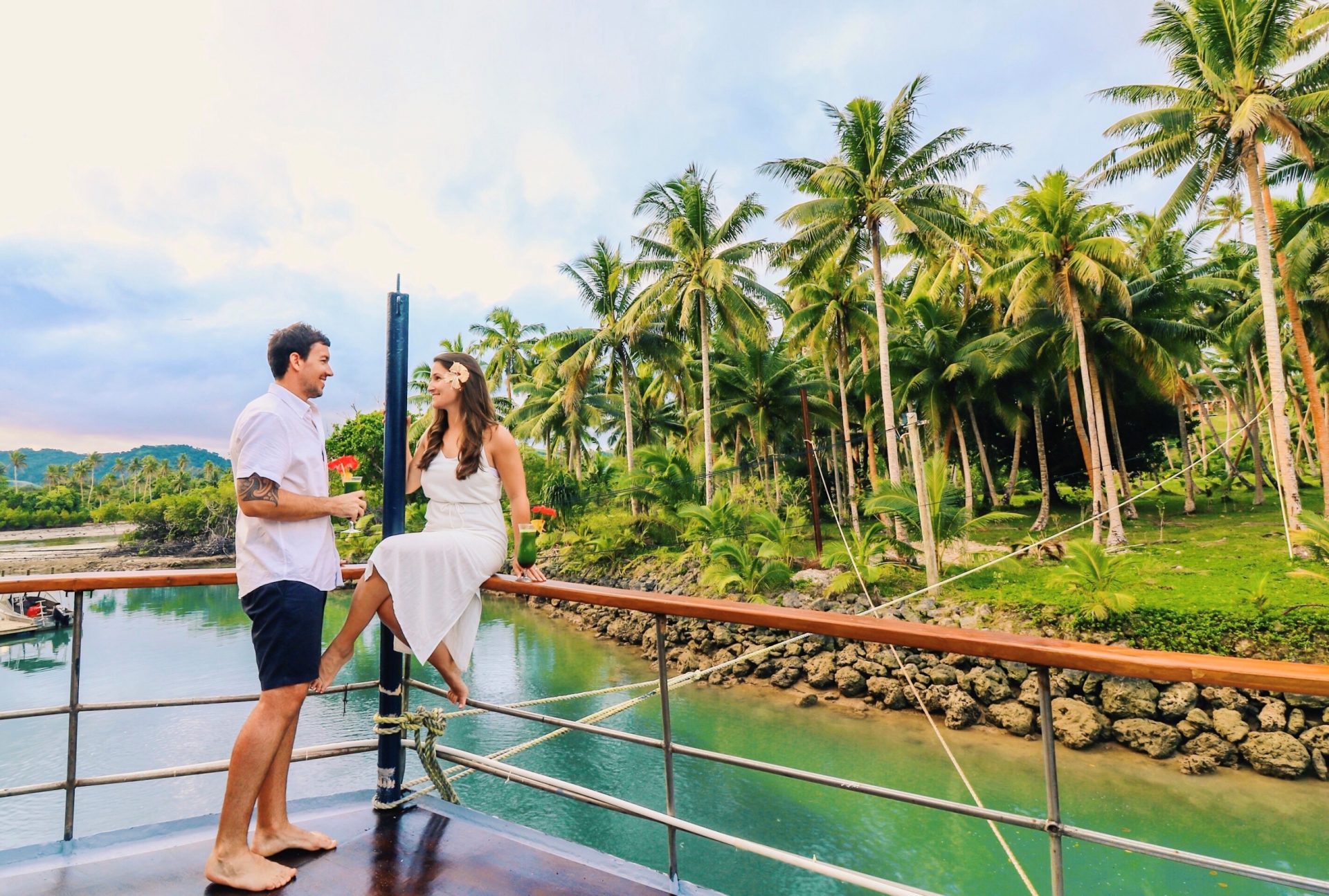 honeymoon couple enjoying cocktails on deck at sunset